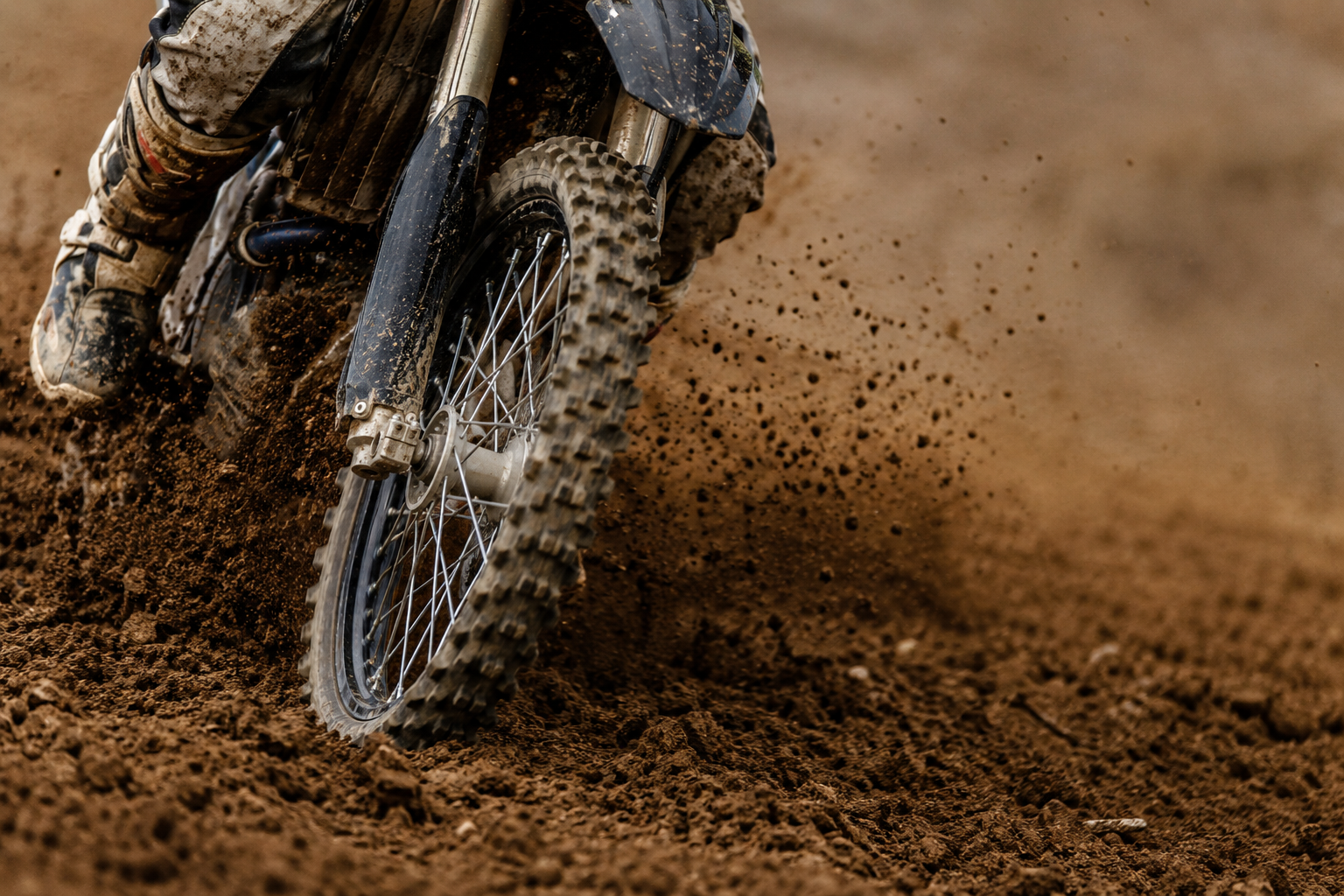 Close-up of a knobby motocross tire throwing dirt.